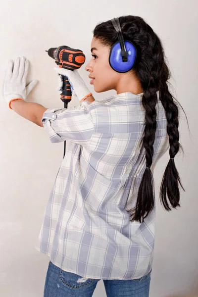 Beautiful young woman drilling wall during renovation of home — Stock Photo