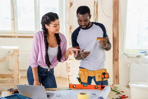 Glückliches junges Paar beim E-Shopping während der Renovierung seines Hauses — Stockfoto