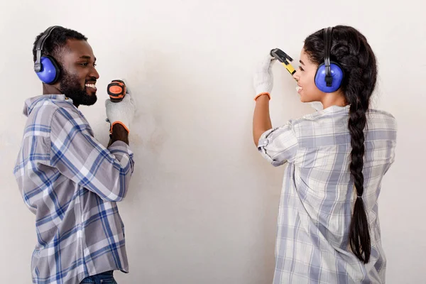 Pareja haciendo la renovación del hogar con taladro y martillo juntos - foto de stock