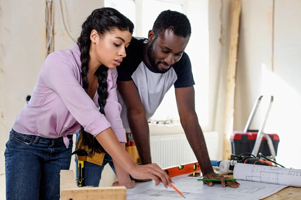 Couple regardant le plan d'architecture tout en faisant la rénovation de la maison — Photo de stock