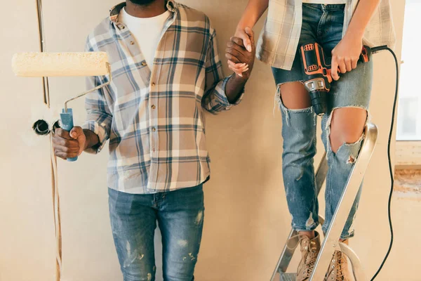 Plan recadré de couple avec brosse à rouler et perceuse faire la rénovation de la maison — Photo de stock