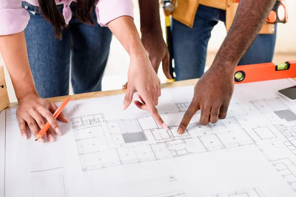 Cropped shot of couple pointing at building plan while making renovation of home — Stock Photo