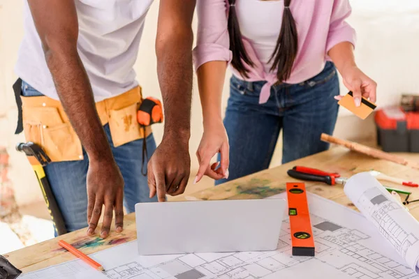 Plan recadré de couple à l'aide d'un ordinateur portable tout en faisant la rénovation de la maison — Photo de stock