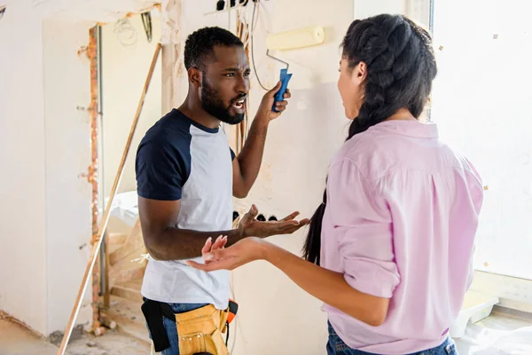 Young couple having quarrel while making renovation of home — Stock Photo