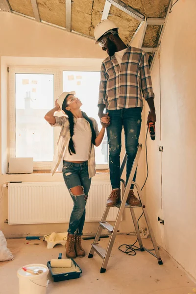 Glückliches junges Paar mit Leiter macht gemeinsam Renovierung des Hauses — Stockfoto