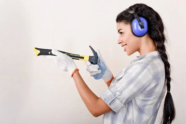 Mujer joven juguetona divirtiéndose con el martillo durante la renovación del hogar - foto de stock