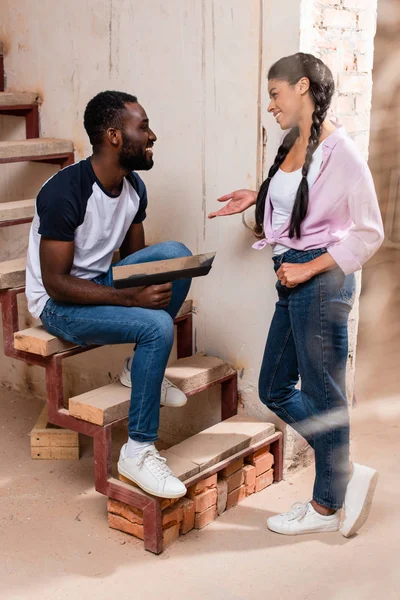 Feliz joven pareja charlando durante la renovación del hogar - foto de stock