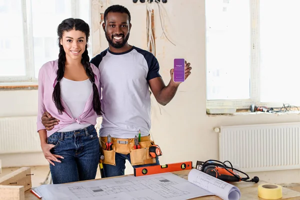 Couple tenant smartphone avec application instagram à l'écran pendant la rénovation — Photo de stock