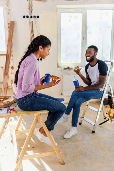 Feliz pareja con bebida gaseosa y pizza relajante mientras se hace la renovación del hogar - foto de stock