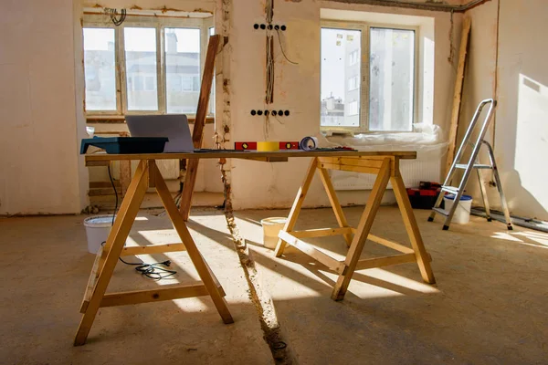 Комната со строительными лесами с инструментами и ноутбуком во время ремонта дома — стоковое фото