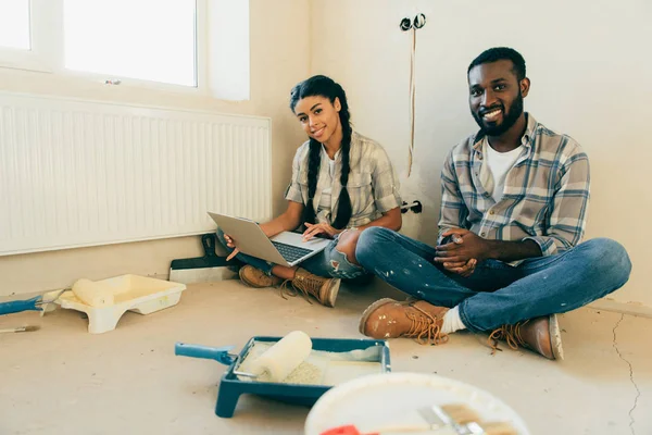 Coppia afro-americana a riposo con il computer portatile durante la ristrutturazione della nuova casa — Foto stock