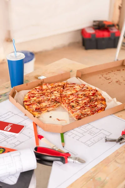 Foco seletivo de pizza, refrigerante, blueprint, ferramentas e smartphone com youtube na tela na mesa — Fotografia de Stock