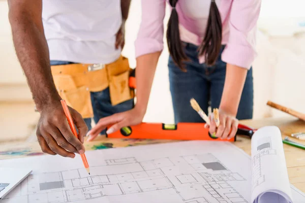 Cropped image of man making notes on blueprint and his girlfriend standing near — Stock Photo