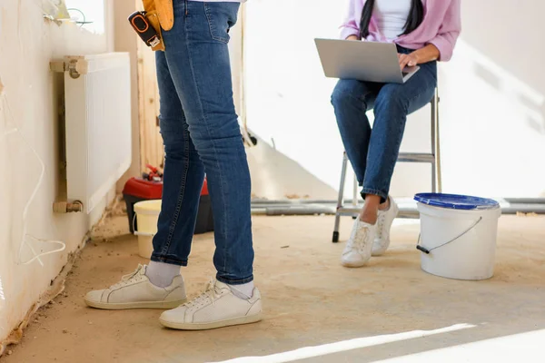 Abgeschnittenes Bild eines Mannes, der arbeitet, während seine Freundin während der Renovierung des Hauses Laptop benutzt — Stockfoto