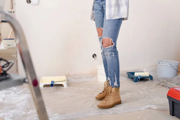 Sección baja de la mujer en jeans con estilo de pie durante la renovación del hogar - foto de stock