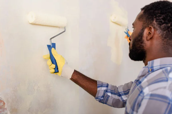 Concentrated african american man painting wall by paint roller — Stock Photo