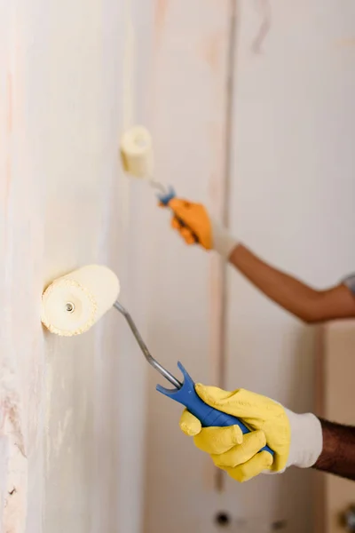 Imagem cortada de parede de pintura de casal por rolos de pintura em nova casa — Fotografia de Stock