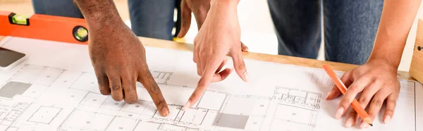 Cropped image of couple pointing by finger at blueprint — Stock Photo