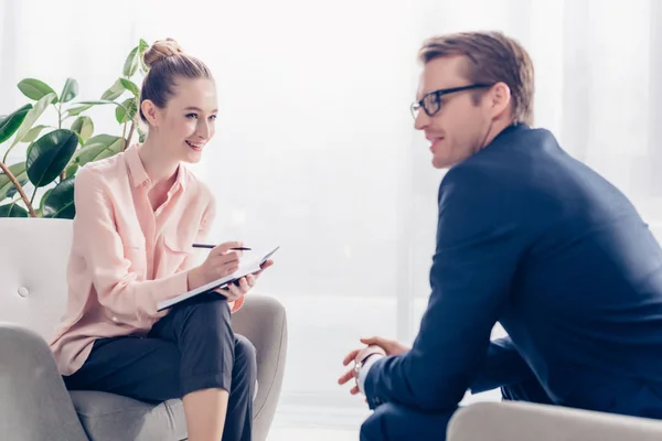 Smiling handsome businessman giving interview to cheerful journalist in office — Stock Photo