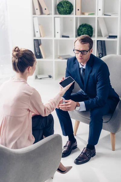 Vue en grand angle de bel homme d'affaires donnant une interview à un journaliste au bureau — Photo de stock