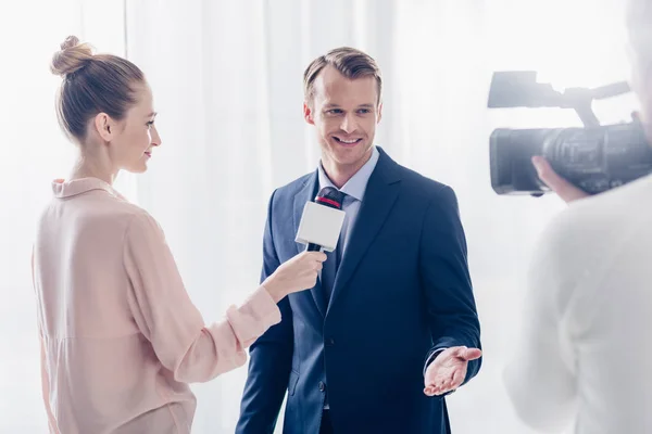 Sorridente bonito empresário dando entrevista em vídeo para jornalista no escritório — Fotografia de Stock