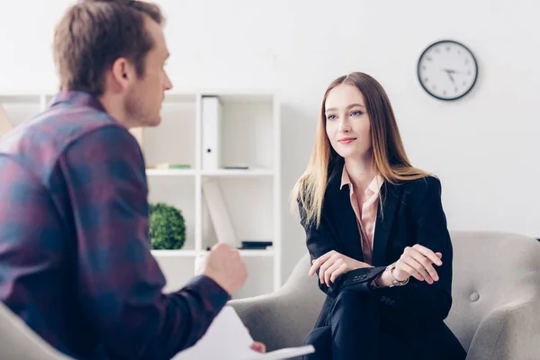 Selective focus of businesswoman in suit giving interview to journalist and looking at him in office — Stock Photo