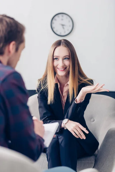 Donna d'affari sorridente in giacca e cravatta che rilascia intervista al giornalista e gesti in ufficio — Foto stock