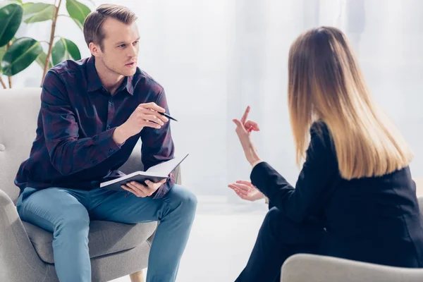 Mujer de negocios en traje dando entrevista a guapo periodista en camisa casual en la oficina — Stock Photo