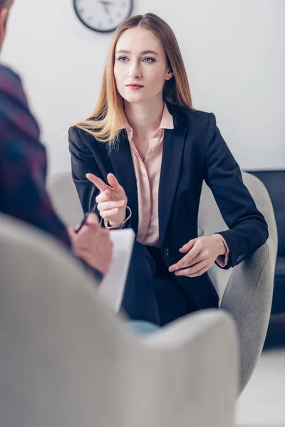 Selektiver Fokus einer Geschäftsfrau im Anzug, die einem Journalisten ein Interview gibt und auf ihn im Amt zeigt — Stockfoto