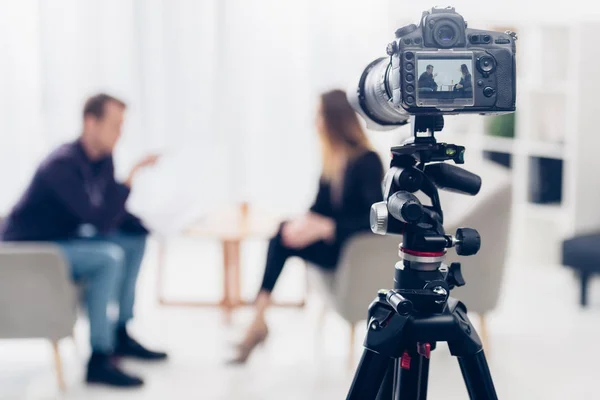 Businesswoman in suit giving interview to journalist in office, camera on tripod on foreground — Stock Photo