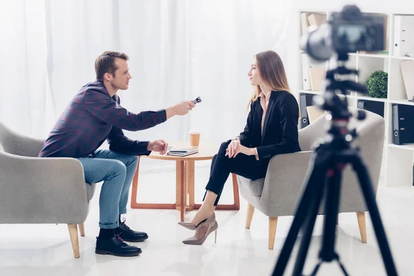 Visão lateral de empresária em terno dando entrevista ao jornalista com gravador de voz no escritório — Fotografia de Stock