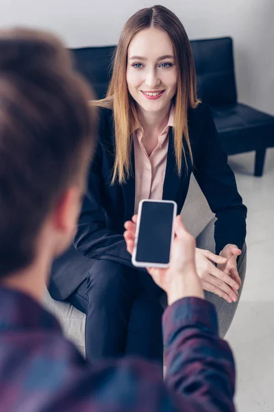 Journalist recording interview with smiling businesswoman on smartphone in office — Stock Photo