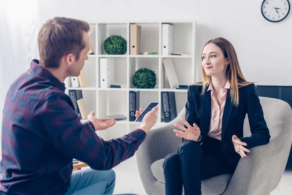 Businesswoman in suit giving interview to journalist and gesturing in office — Stock Photo