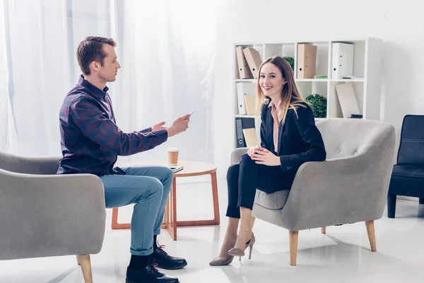 Smiling businesswoman in suit giving interview to journalist in office — Stock Photo