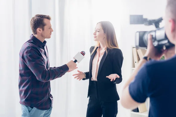 Bela mulher de negócios em uso formal dando entrevista ao jornalista e gesticulando no escritório — Fotografia de Stock