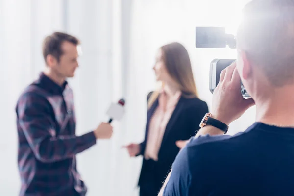 Selective focus of businesswoman in suit giving interview to journalist at workspace — Stock Photo