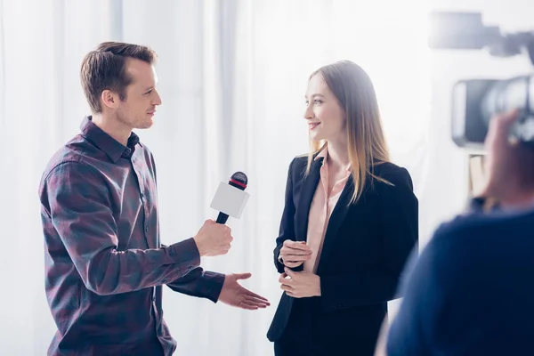 Beautiful businesswoman in suit giving interview to handsome journalist in office — Stock Photo