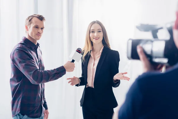 Bela mulher de negócios em terno dando entrevista ao jornalista e gestos no escritório — Fotografia de Stock