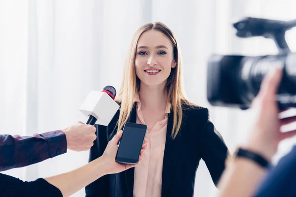 Mulher de negócios bonita feliz no terno que dá a entrevista a jornalistas no escritório — Fotografia de Stock