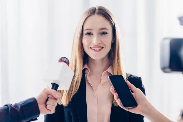 Smiling attractive businesswoman giving interview to journalists in office — Stock Photo