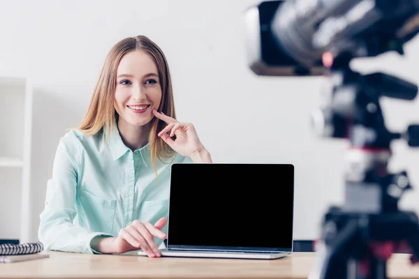 Smiling attractive female freelancer recording vlog in office, laptop with blank screen on tabletop — Stock Photo