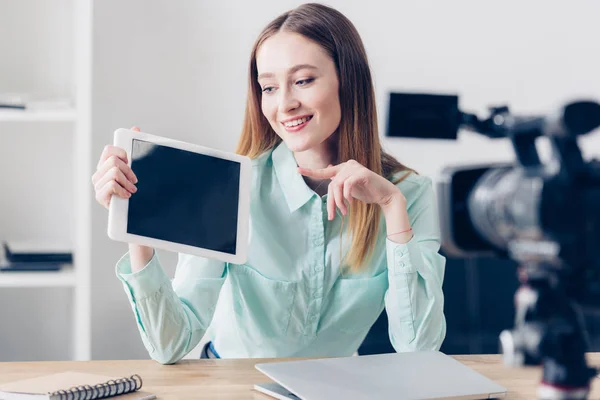 Lächelnd attraktive weibliche Video-Bloggerin Aufnahme vlog und zeigt auf Tablet mit leerem Bildschirm im Büro — Stockfoto