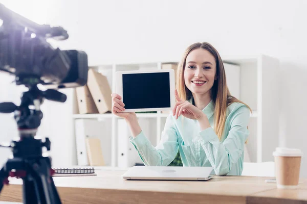 Sorrindo atraente fêmea vídeo blogger gravação vlog e mostrando tablet com tela em branco no escritório — Fotografia de Stock