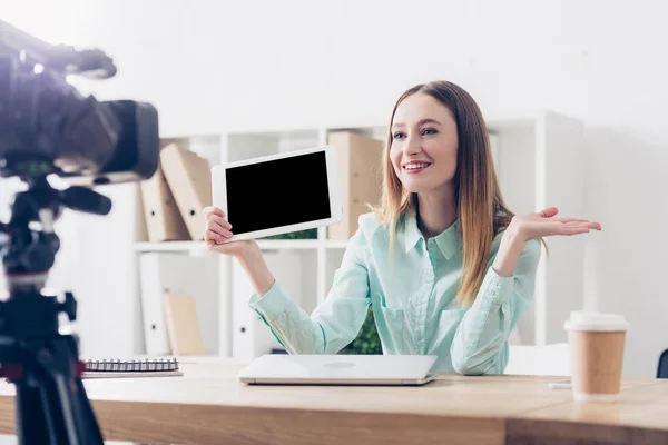 Smiling attractive female video blogger recording vlog and holding tablet with blank screen in office — Stock Photo