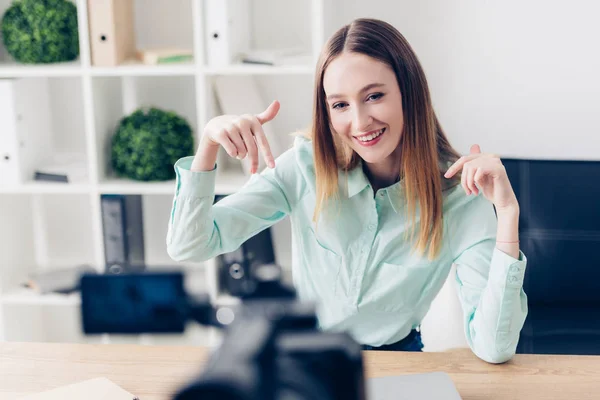 Sorridente attraente video blogger femminile registrazione vlog e gesti in ufficio — Foto stock