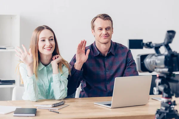 Smiling video bloggers recording vlog and waving hands in office — Stock Photo