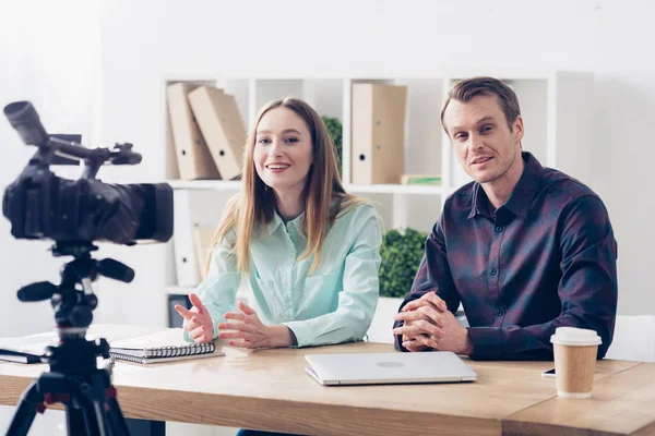 Smiling video bloggers recording vlog at table in office — Stock Photo