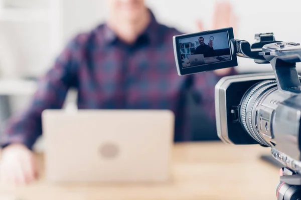 Cropped image of male video blogger recording vlog in office, camera on foreground — Stock Photo