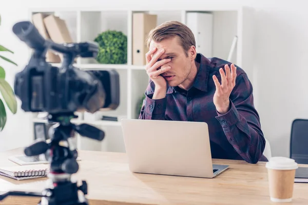 Schöner männlicher Videoblogger, der Vlog aufzeichnet und im Büro durch die Finger schaut — Stockfoto