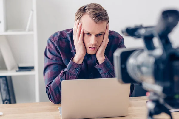 Cansado guapo vídeo blogger tocando cabeza y grabación vlog en oficina - foto de stock